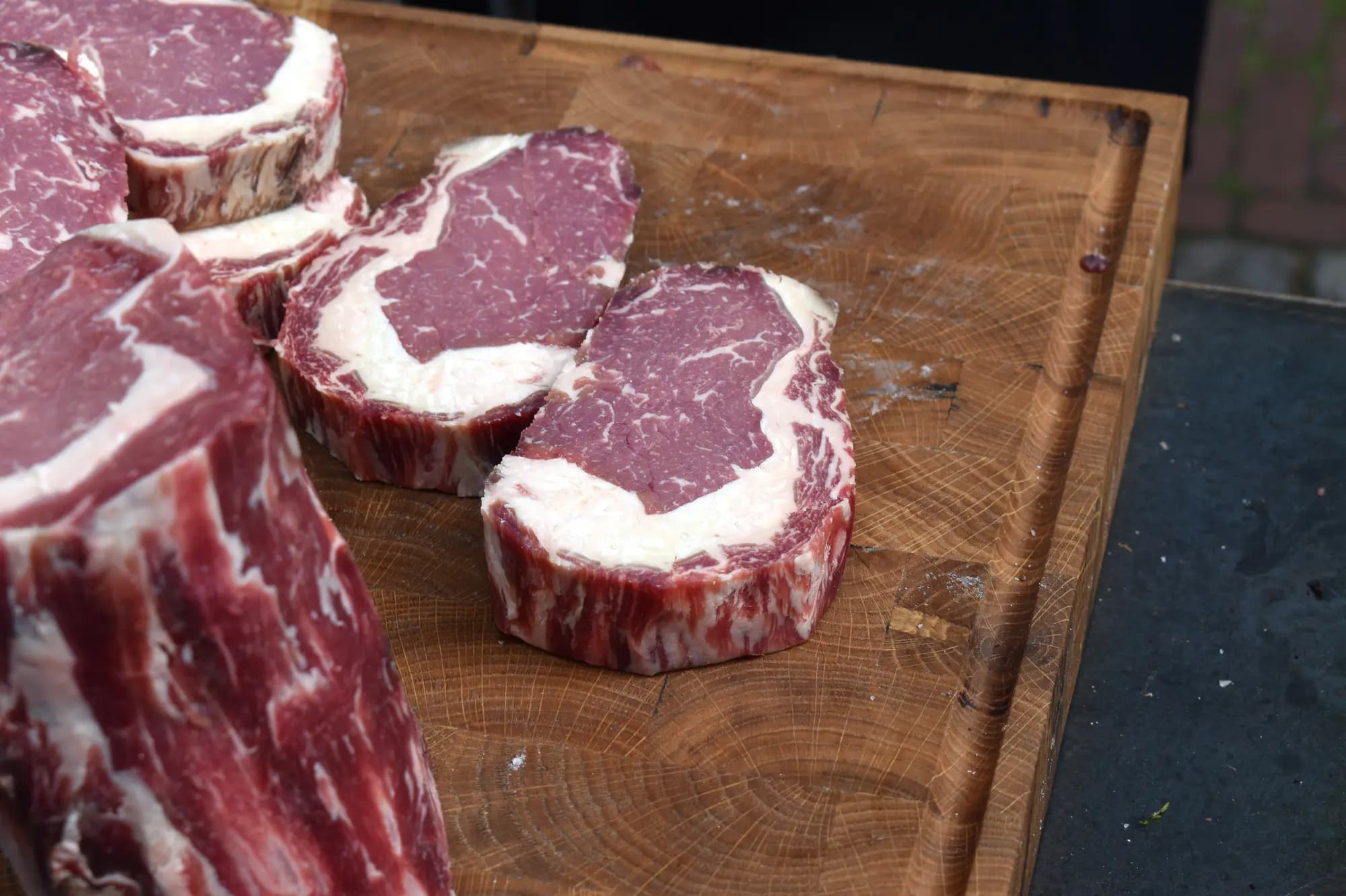 Dikke plakken rauwe ribeye met vetrand op een houten snijblok buiten