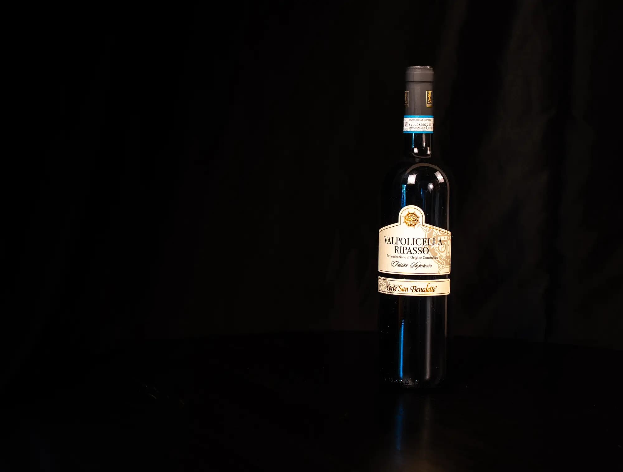 Fles Valpolicella Ripasso Classico Superiore van Corte San Benedetto, frontaal etiket op donkere tafel