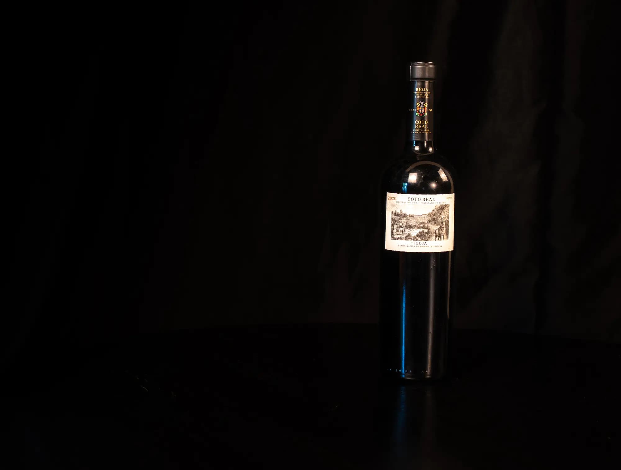 Fles Coto Real Rioja met klassiek gravure-etiket, uitgelicht tegen zwarte achtergrond